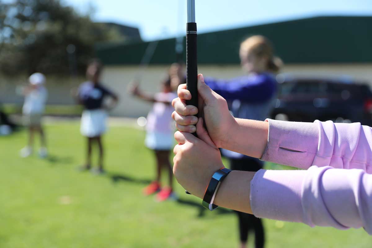 Email golfer practicing grip on club during a group class.